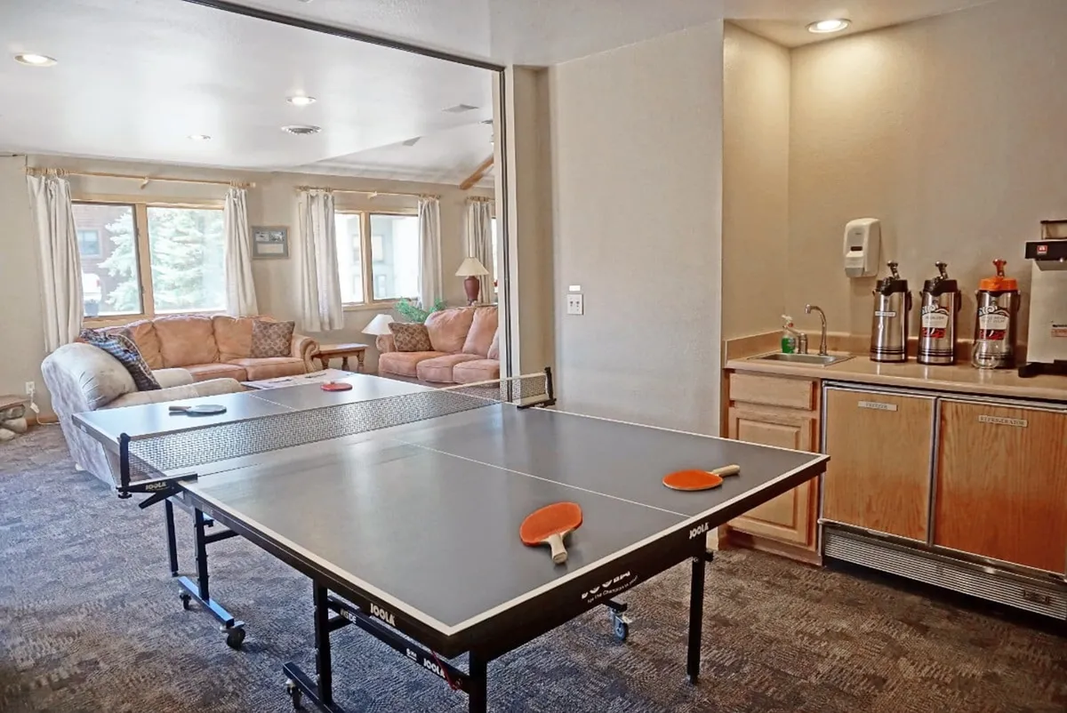An interior clubhouse space with a ping pong table, sofa, and kitchenette—perfect for socializing and friendly competitions after a day outdoors.