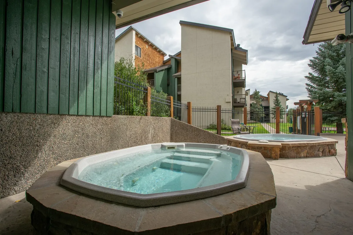This exterior image features inviting hot tubs surrounded by greenery, with resort buildings visible in the background. The tranquil atmosphere suggests relaxation and opportunities for rejuvenation during breaks from work.
