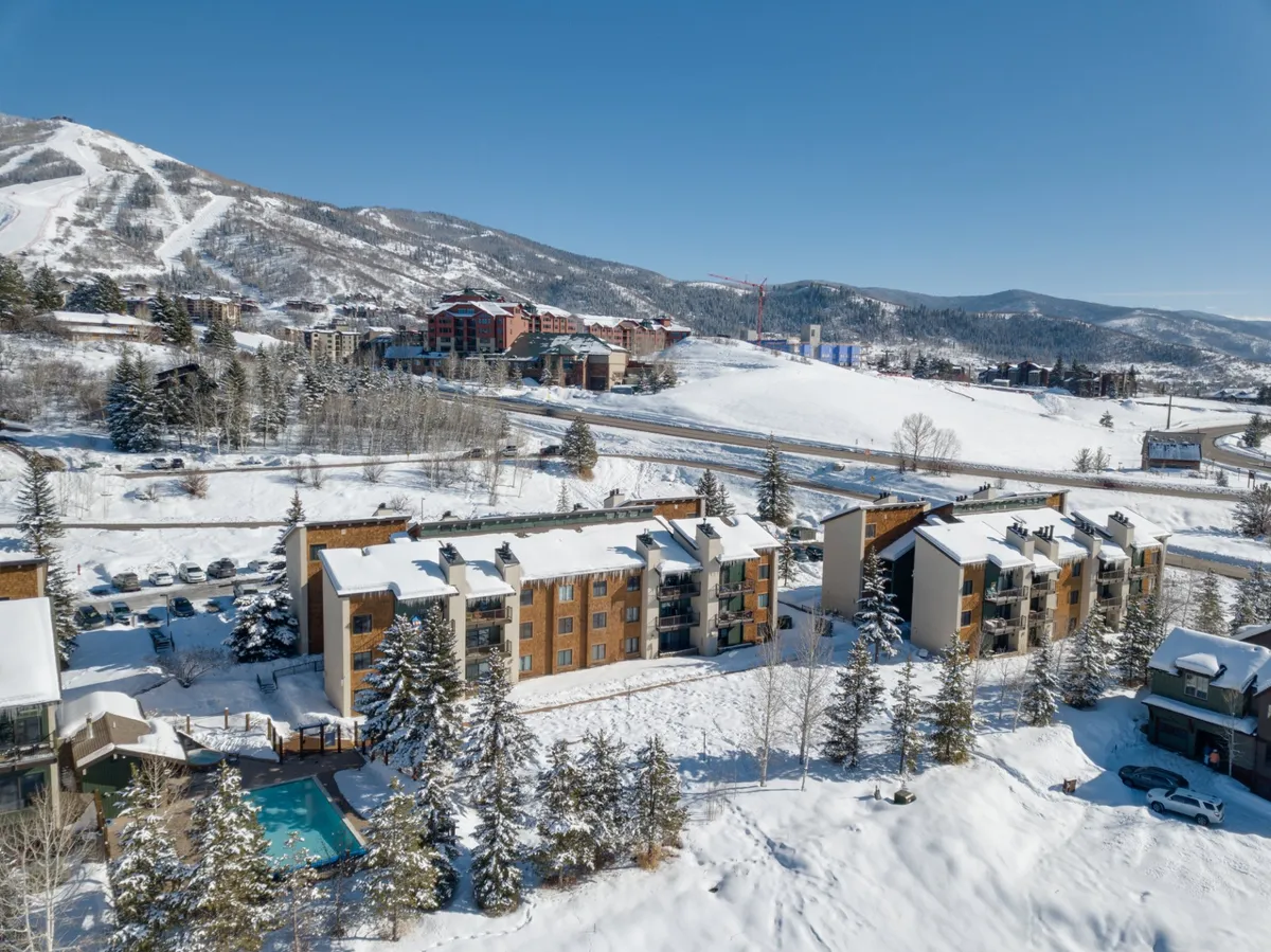 An inviting winter scene featuring snow-covered buildings, a swimming pool, distant ski slopes, and trees, all set against a cozy, adventurous backdrop. The image blends outdoor recreation with après-ski relaxation.